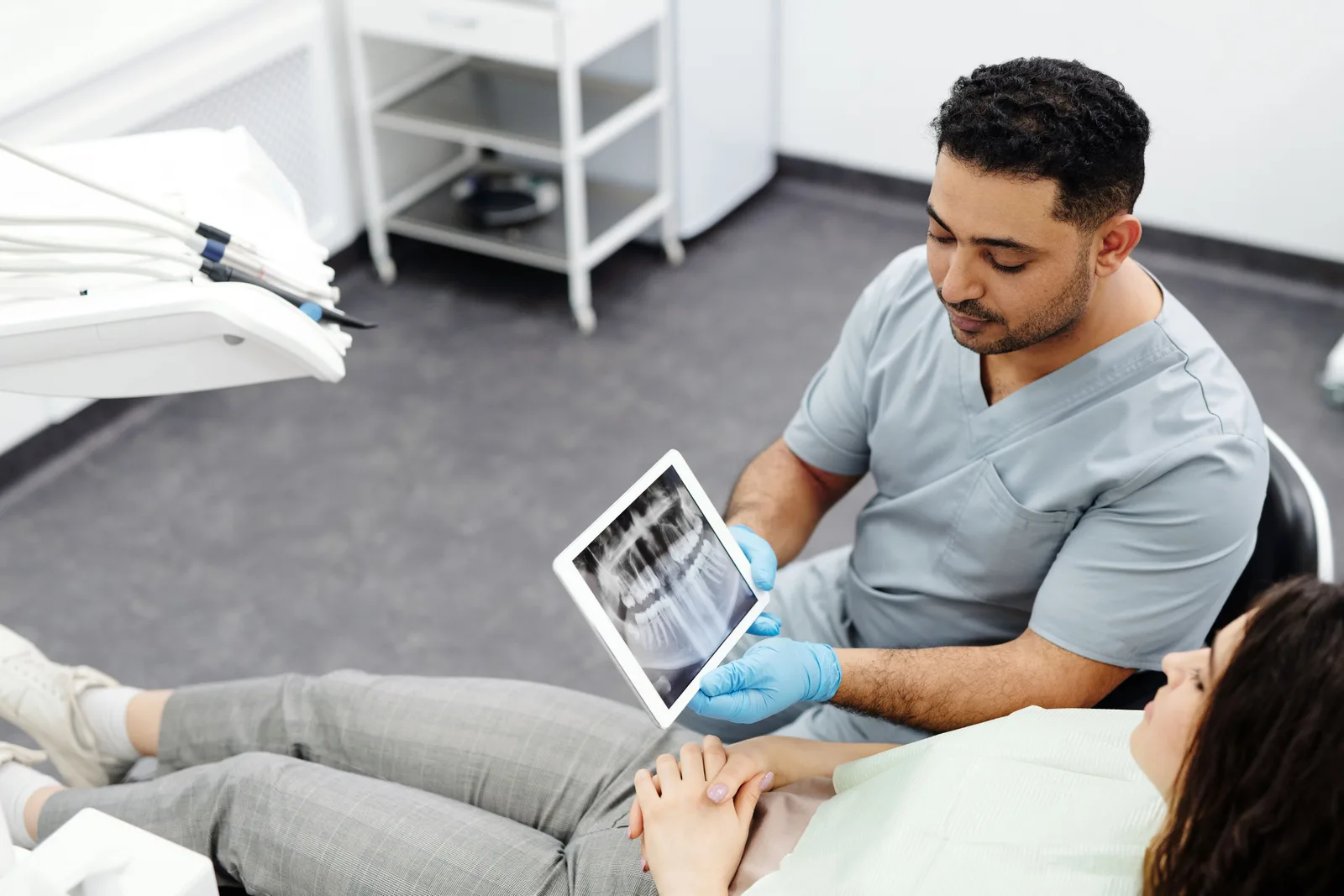 Dentista mostra uma radiografia panorâmica em tablet para a paciente